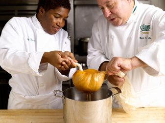 Mattel and a student drain a shellfish bisque through rinsed doubled cheesecloth. Photo courtesy of CIA.